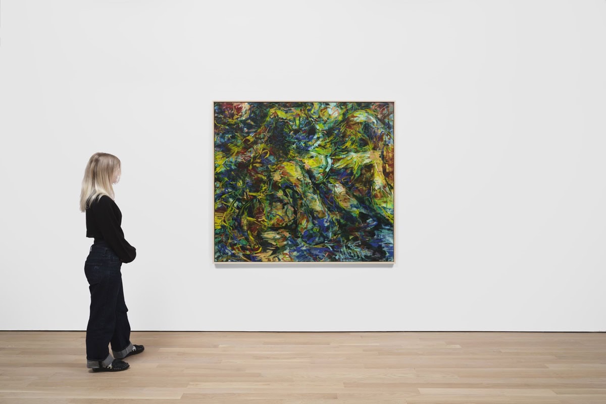 A woman stands in gallery looking at a large painting