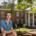 Sam Hey poses for a potrait on front campus, with Martin Science in the background behind him