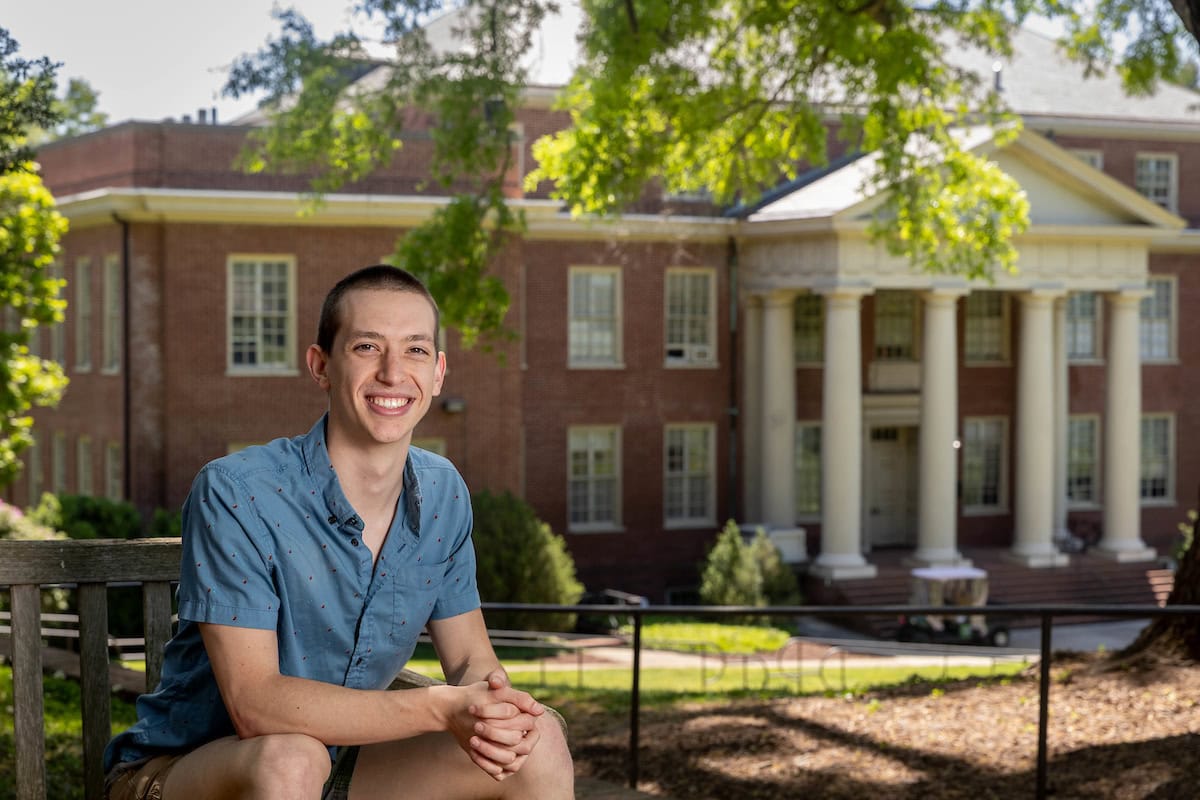 Sam Hey poses for a potrait on front campus, with Martin Science in the background behind him