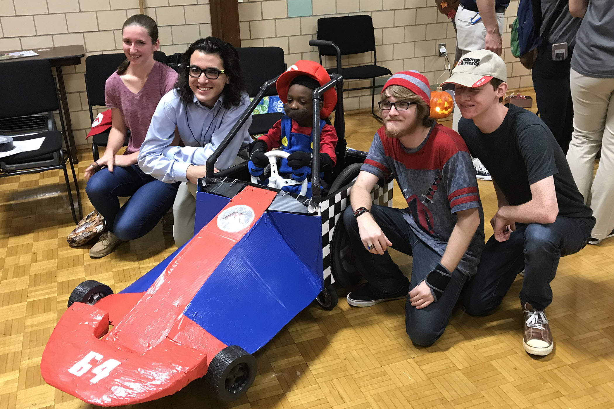 Randolph College physics student present their custom built Mario wheelchair costume to a local boy.