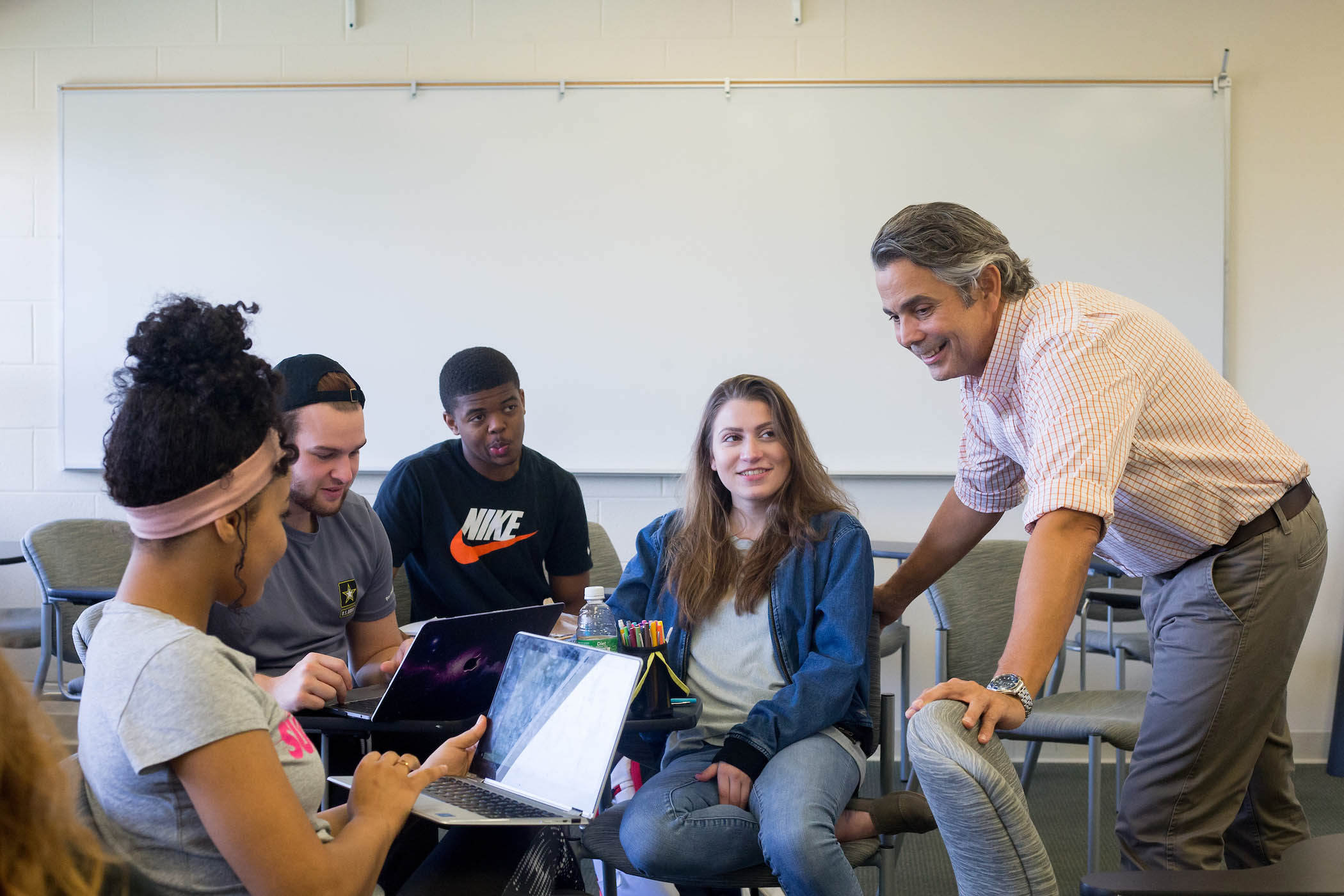 Professor Julio Rodriguez checks in with a group of 4 students in a breakout discussion session during class.