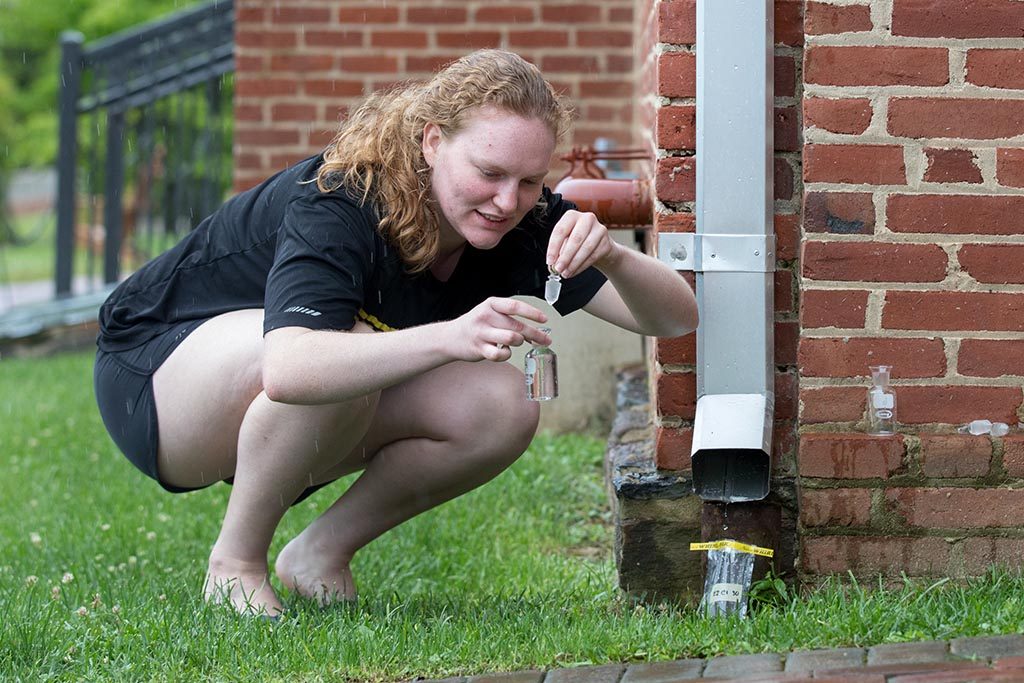 Environmental science student tests the quality of rainwater draining off of campus rooftops.