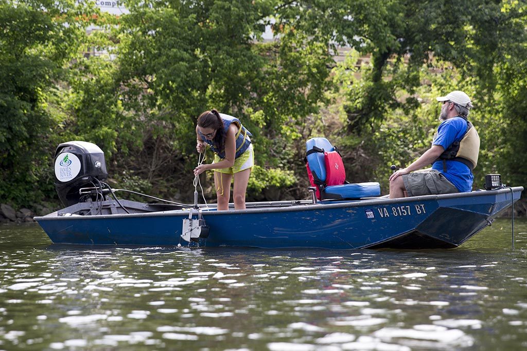 Environmental science students collect water samples near a dam to test for contamination.